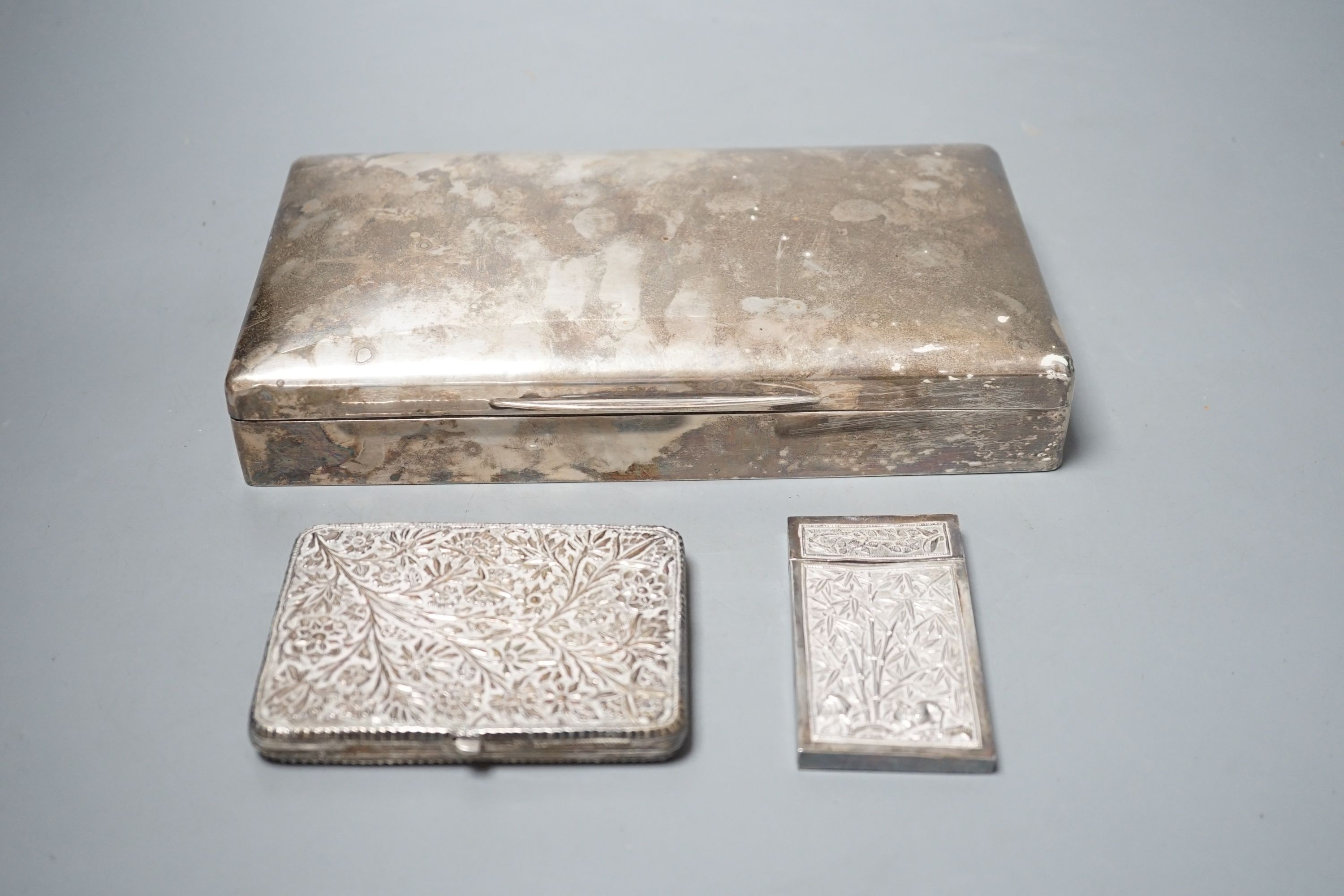 A George V silver mounted cigarette box, London, 1913, 23cm, a Chinese? white metal card case(a.f.) and an Indian? white metal cigarette case.